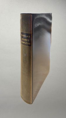 un vieux livre à la couverture dorée posé sur une table blanche