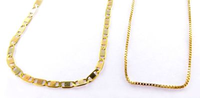 two pieces of gold necklaces on a white surface