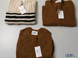 trois pulls et un gilet sont exposés sur une table