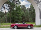 a red convertible car parked under an arch in the middle of the road