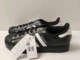 chaussures Adidas Superstar noires et blanches avec une étiquette de prix sur le côté