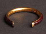 a close up of a gold and red bracelet on a black surface