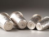 four silver cups are lined up on a table