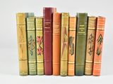 several old books are lined up in a row on a white surface