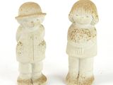 two ceramic figurines of a boy and a girl