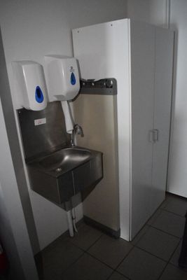 une photo de toilettes publiques avec un lavabo et un sèche-mains