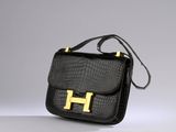 a black handbag with a gold h on the front