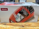 a red and black typewriter in a box on a wooden table