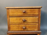 an image of a small wooden chest of drawers on a gray background