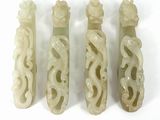 four carved jade bottles with designs on them on a white surface