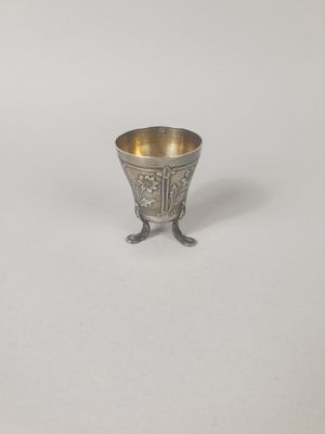 une coupe en argent ancien posée sur un socle, sur une surface blanche