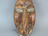 une image représentant un masque en bois sur une surface grise