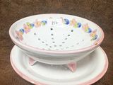 une assiette blanche bordée de rose et un bol blanc orné de fleurs