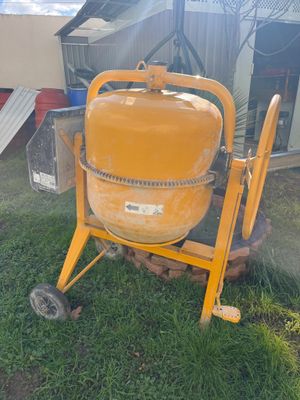 a yellow cement mixer sitting in the grass