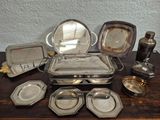 a lot of silver plated items on a wooden table