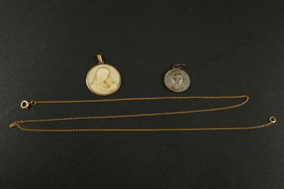 deux colliers en or et en argent et une pièce de monnaie posés sur une surface noire
