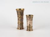 deux vases en or posés l'un à côté de l'autre sur une surface blanche