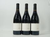 trois bouteilles de vin sont alignées sur une surface blanche