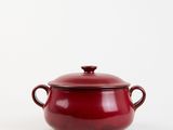le grand pot rouge est posé sur une surface blanche