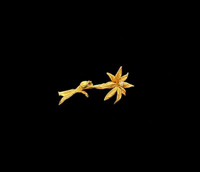 un gros plan d'une broche en forme de fleur dorée sur fond noir
