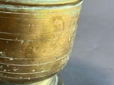 a gold vase with a wooden spoon next to it