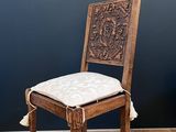 an old wooden chair with a white cushion and tassel on the seat