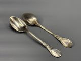 two silver spoons sitting next to each other on top of a table