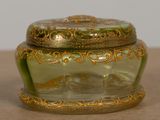 a green glass box with a gold decoration on it