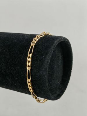 a close up of a gold chain bracelet on a black ring holder