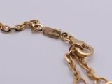 a close up of a gold chain bracelet on a white surface