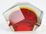 a red and yellow glass object on a white surface