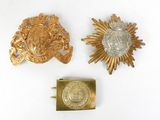 two gold and silver brooches and a coin on a white surface