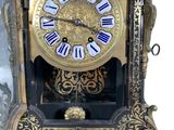 a gold clock with blue roman numerals on the face