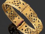 gros plan d'un bracelet en or sur une surface noire