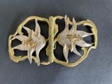 gold plated broochle with flowers and leaves on a black surface
