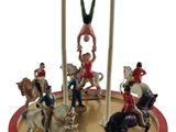 des figurines représentant des personnes à cheval sur un manège, avec un homme à cheval