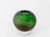 un vase en verre vert orné d'une bande rouge