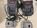 four batteries and two chargers sitting on a table