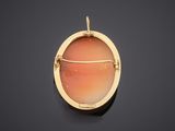 a close up of a gold pendant with a red stone in the center