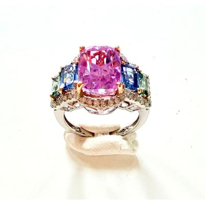 une bague sertie de diamants roses et bleus sur un fond blanc