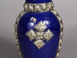 a blue vase with a gold decoration on it