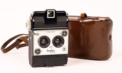 un sac marron et un appareil photo marron posés sur une surface blanche