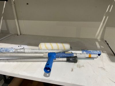 un tuyau métallique et un outil bleu posés sur une table blanche