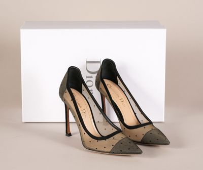 une paire de chaussures à talons hauts noires et argentées posées devant une boîte blanche