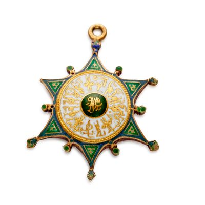 un gros plan d'une médaille en forme d'étoile ornée d'un motif vert et or