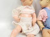 two dolls sitting next to each other on a white surface