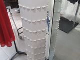 a tall white pedestal with a lot of clothes on it