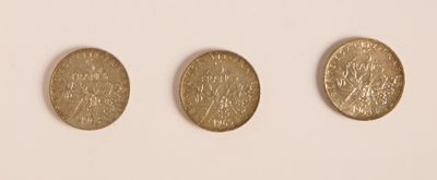 trois pièces d'or posées les unes à côté des autres sur une surface blanche