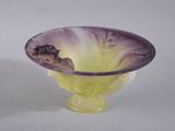 un saladier en verre violet et jaune posé sur une table blanche