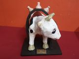 statue d'une vache à cornes posée sur un socle noir, sur une surface rouge